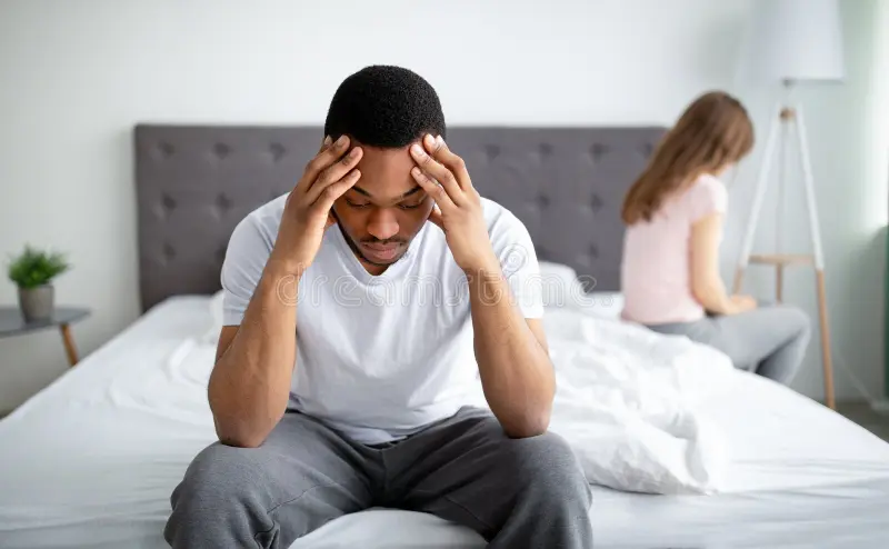 erectile dysfunction sex relationship problems concept depressed young black men sitting bed his offended girlfriend 227417779